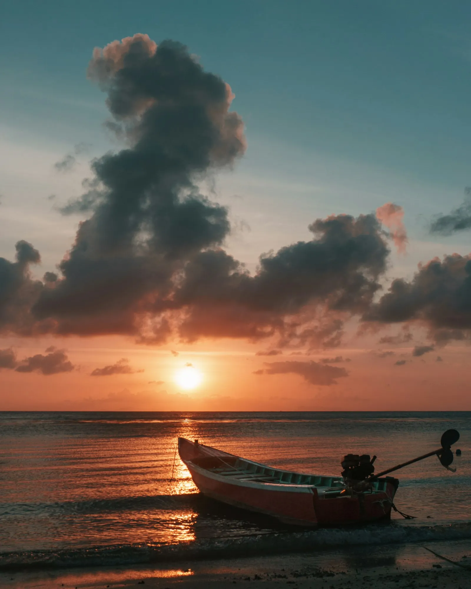 Small boat on the water under a dramatic sunset sky