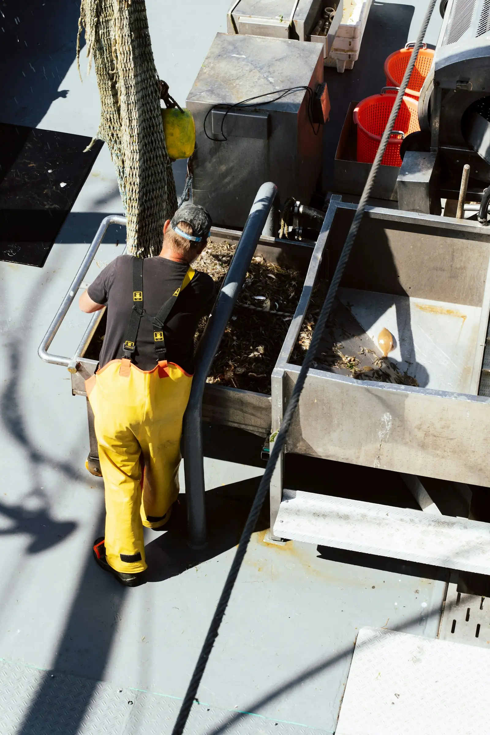 Deckhand in yellow bib overalls working on a boat