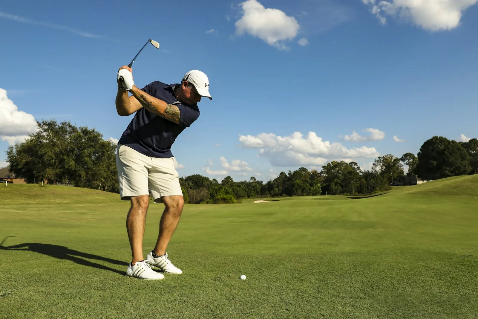 Golfer mid-swing on a sunny fairway