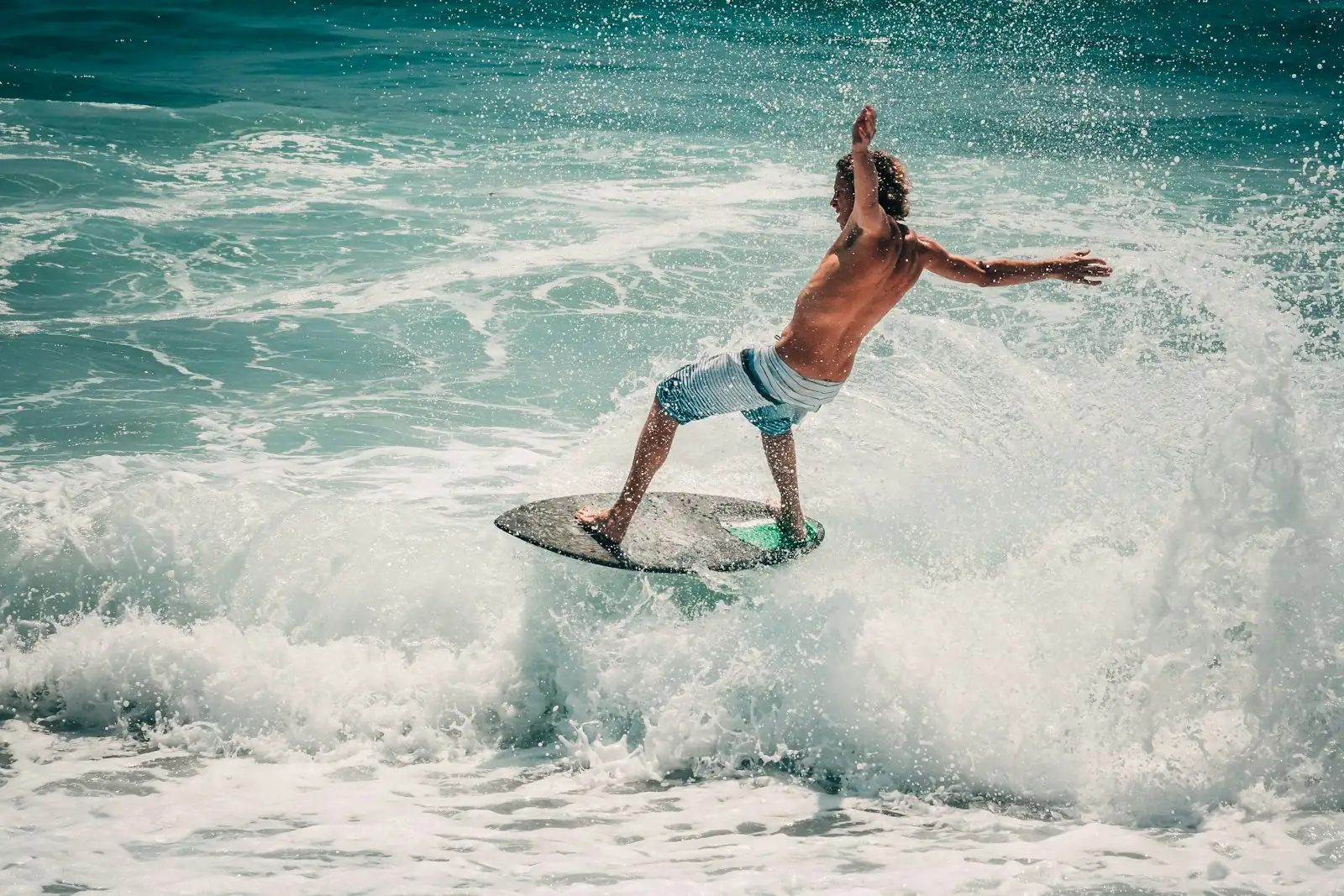 Skimboarder carving through white water in the shorebreak